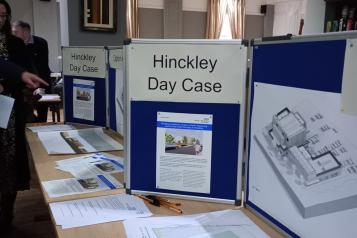 A table showing papers and a display stand for Hinckley Day Case Unit